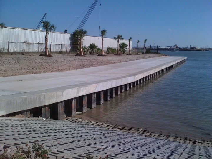 Completed concrete waterfront dock with palm trees along the shoreline